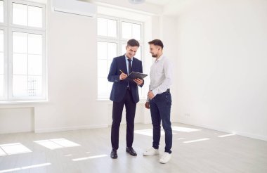 Yeni bir ev ya da ofis sunarken müşteriye danışmanlık yapan pozitif emlakçı. Emlakçı, mülkü sergileyerek potansiyel alıcı veya kiracılara profesyonel danışmanlık ve anlayış sunuyor.