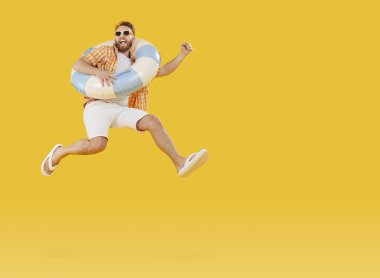 Güneş gözlüklü, lastik halkalı, neşeli turist stüdyo sarısı arka planda izole edilmiş. Komik turist yaz tatiline çıkıyor. Tatil ve seyahat kavramı.