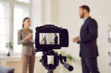 Röportajı kaydeden ya da canlı yayın yapan bir kameranın görüntüsünü kapat. Sahne bir muhabir ve bir konuk arasındaki etkileşimi, bir TV programının, haber programının ya da halkla ilişkiler şirketinin bir parçasını yakalıyor..
