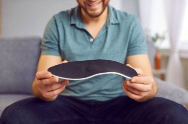 Yeni ortopedik spor ayakkabısı tutan bir adam. Yürümek, koşmak, yakın durmak için. Ayak bakımı, düz taban, ortopedik hastalıkları önleme, acıyı dindirmek için rahat tıbbi ortotik ayakkabılar giyme, destek 
