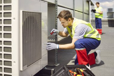 Tamirci ya da elektrikçi çatıda bir tornavida kullanarak bakım, onarım ya da denetim yapıyor. Sistemin düzgün işlemesini ve verimliliğini sağlamak.