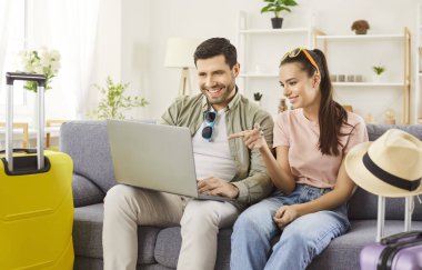 Uçak bileti, otel rezervasyon hizmeti internetten, yeni evli çiftin seçtiği bavullar valizler, tekerlek bavulu, plaj şapkası, turizmden, seyahatten, balayı planından keyif almaya hazır.