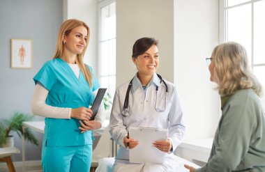 Gülümseyen dost canlısı hemşire ve kadın doktor hasta genç kadın hastayla konuşuyor klinikte tedavi sırasında koltukta oturup tedavisini tartışıyorlar. İlaç ve sağlık hizmetleri kavramı.