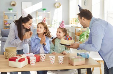 Mutlu ebeveynler evde birlikte oturup doğum günlerini kutluyorlar. Küçük aileler ve iki çocuk doğum günü partisini kutluyorlar. Aile ve tatil kutlaması konsepti.