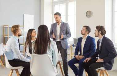 İş adamlarından oluşan bir grup daire şeklinde konuşuyor, yeni projeyi tartışıyorlar, iyi sözleşme şartlarını ve koşulları göz önünde bulunduruyorlar, işi çözüyorlar, resmi toplantı düzenleyen erkek lider.