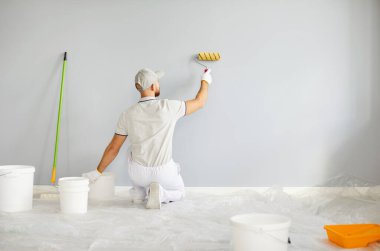 Profesyonel hizmet, çalışan ressam, inşaat işçisi, boya fırçası ile üniforma boyama, ticari dekorasyon, pürüzsüz, profesyonel duvar kapağı, arka