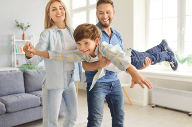 Üç kişilik mutlu bir aile evdeki oturma odasında çocukla eğleniyor ve uçak oyunu oynuyorlar. Anne, baba ve küçük sevimli oğulları birlikte evde vakit geçiriyorlar..