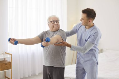 Yaşlı, tombul, yaşlı, yaşlı bir emekli hasta halterli rehabilitasyon egzersizi yapıyor mutlu gülümseyen genç doktor fizyoterapist ya da sağlıkçı doktorun yardımıyla. Fizyoterapi kavramı