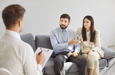 Çift terapisi, erkek, kadın bireysel terapi sırasında erkek danışmana kişisel ve aile sorunlarını anlatır, psikolog hastaları dinler, psikoloji yardımı için notlar alır.