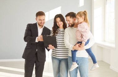 Emlakçı ve küçük kızı olan mutlu aile çifti yeni bir eve taşınıyor, ev kiralamak ya da satın almak için daire belgeleri, geniş modern yaşam için konforlu konutlar kiralıyorlar. 