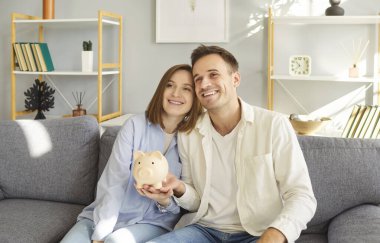 Mutlu aile çifti evde birlikte oturur, kumbaralarını tutarlar, para biriktirirler ve kazanç, finans ve yatırımları tartışırlar. Birlikte finansal gelecek kurmaya odaklanıyorlar..