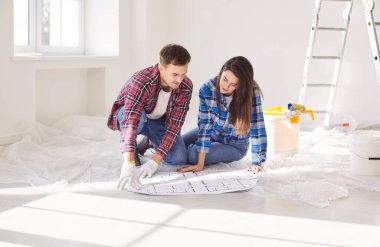 Dost canlısı evli çift yeni bir ev projesini tartışıyor, taslakları gözden geçiriyor, tadilata hazırlanıyor ve gelecekteki inşaat planları hakkında düşünceli bir sohbete girişiyor..