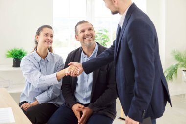 Konsültasyon sırasında mutlu çift müvekkil ve avukat el sıkışırken, müşteriler ve emlak komisyoncusu, temsilcisi, ev satıcısının ofiste el sıkışması, mülk alımını kutlaması, toplantı... 