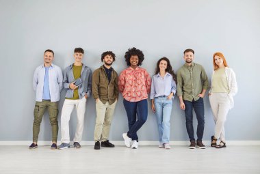 Gri arka planda bir arada duran çok uluslu pozitif insanların grup portresi. Mutlu ve destekleyici bir grup ortamında topluluk, çeşitlilik ve birlik.