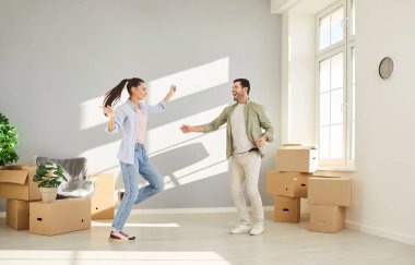 Neşeli kadın ve erkek yeni daireye taşındığı için mutlu. Odada tasasız bir şekilde dans ediyor. Kutularını açmış, taşınmayı kutluyor. Memnuniyetle yeni erkek ve kadın ev sahipleri. 