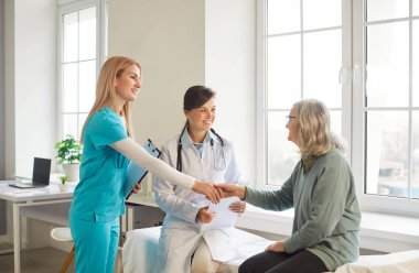 Doktor ve hemşire kliniklerinde yaşlı ve hasta bir kadınla tanışıyor, profesyonel danışmanlık yapıyor ve gelecekteki tedaviler hakkında konuşuyorlar. Yaşlı kadın emeklinin hastanede sağlık kontrolü var..