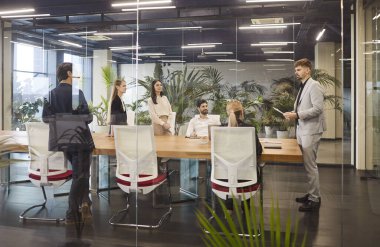 Genç kendine güvenen bir grup şirket çalışanı konferans sırasında modern ofiste oturup yeni iş projelerini tartışıyor. Takım çalışması konsepti.