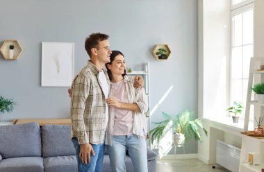 Mutlu aile çifti evde kucaklaşıp gülümsüyor, mutluluk ve sevgi saçıyor. İlişkilerindeki bu hassas anı paylaştıkları için güçlü bir bağ ve neşeli bir bağ ya da birliktelik çok bariz..