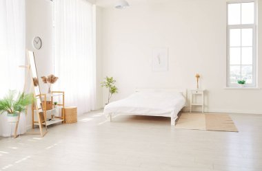 Moda mobilyaları, bitkiler, halı, yatak ve şık ev dekorlarıyla İskandinav tarzında modern çağdaş ev yatak odasının fotoğrafı. İç tasarım kavramı.