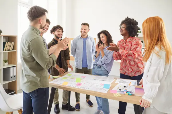 Çeşitli başarılı genç iş adamları, günlük kıyafetlerini giyip iş projelerini tartışırken alkışlıyorlar. İş yerinde birlikte çalışan iş arkadaşları. Takım çalışması konsepti.