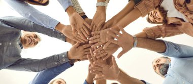 Çeşitli mutlu erkek ve kadınların iş birliğinin bir sembolü olarak kollarını kavuşturmalarının alt görüntüsü. Çember oluşturup birlik ve takım çalışması sergileyen insanlar. İnsan desteği kavramı.