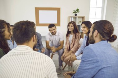 Bir grup terapi seansı sırasında bir çemberde oturan, konuşan ve gülümseyen farklı insanlar. Mutlu, neşeli, pozitif ve olgun genç erkek ve kadınların oluşturduğu bir ekip toplanıyor.