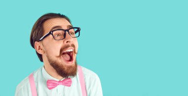 Komik, mutlu, heyecanlı, şaşkın, ağzı açık, gömlek, pantolon askısı, papyon ve gözlük takan, boş turkuaz mavisi reklam arkaplanında çığlık atan, ağzı açık, şaşkın, şaşkın adam. İndirim, indirim konsepti