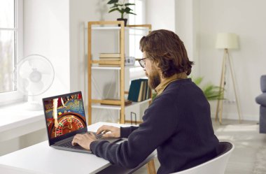 Beyaz adam milenyum boyunca online kumarhanede rulet tekerleği ve krupiye eliyle monitöre bakarak para kazanmayı umarak oynadı.