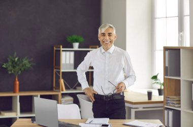 Modern bir iş merkezinin ofisinde içtenlikle gülümseyen kendinden emin ve pozitif bir iş adamının portresi. İş, güven ve iş adamları kavramı.