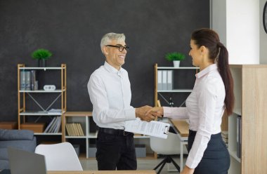 İş adamları kağıt imzaladıktan sonra el sıkışıyor. Mutlu erkek ve kadın girişimciler ofiste buluşur, güven ve karşılıklı menfaate dayalı anlaşmalar yapar ve işbirliği için birbirlerine teşekkür ederler.