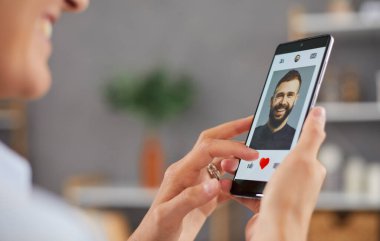 Gülümseyen kadın sosyal medyada fotoğraf çekmeyi ya da internetteki flört uygulamasını kullanmayı seviyor. Akıllı telefon uygulamasındaki kalp ikonunu kapat. Çevrimiçi randevu kavramı.