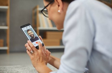 Cep telefonu ekranında randevu uygulaması ya da site. İlişki sitelerinde ya da başvurularda profilleri araklayan ve seven neşeli tatmin olmuş bir kadın. Bekar bir kadın aşkı, partneri ve sevgilisini bulmak için akıllı telefonu kullanıyor..