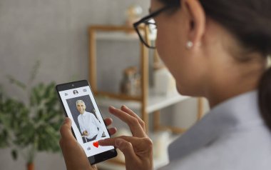 Aşkı bulmak. Randevu başvurularındaki erkeklerin profillerini cep telefonuyla inceleyen bir kadın. Kadın, ekranda görünen adamı sevmek için kırmızı kalp butonuna basar..