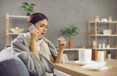 Grip ya da soğuk algınlığı geçiren mutsuz bir kadın doktor çağırıyor. Sıcak battaniyeye ya da ekose kumaşa sarılmış hasta bir kadın evdeki koltukta oturup termometreye bakıyor ve doktorla telefon görüşmesi yapıyor.