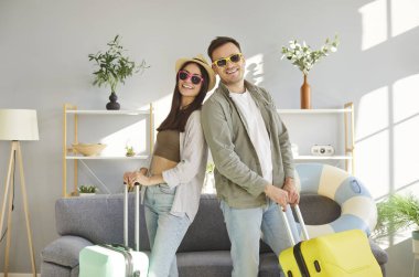 Mutlu turistler, güneş gözlüklü balayı çifti, evde genç bir aile, seyahat planı, yaz tatili kumsalı hayali, evliliği kutlamak için seyahat çantası.