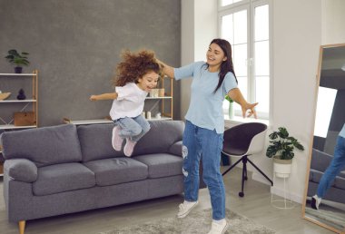 Mutlu aile evde eğleniyor. Anne ve küçük çocuk oturma odasında ses geçirmez duvarlarla komşuları rahatsız etmeden oynuyorlar. Gülümseyen anne kanepeden atlarken kızlarının elini tutuyor.