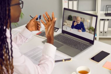 Afro-Amerikalı bir kadının laptop monitörüne baktığı iş yerindeki masada oturduğu ve erkek arkadaşlarıyla internet üzerinden ya da video konferans yaptığı görüntüler...