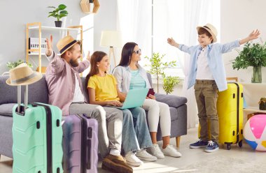 Dört kişilik mutlu bir aile, çocuklar internet üzerinden bilet alıyor ve dizüstü bilgisayarlarıyla yaz tatilini planlayan bavullarıyla oturma odasındaki koltukta oturuyor. Tatil gezisi konsepti.