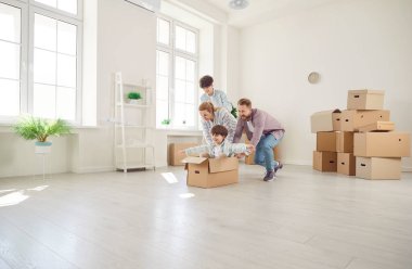 Çocuklar ve karton kutularla dolu yeni bir evde mutlu ebeveynler oturma odasında. Taşındıktan sonra neşeli duygular. Mobilyasız boş bir oda. Aile Taşıma Konsepti