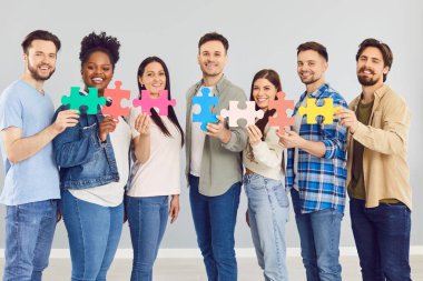 Mutlu gülümseyen iş adamları grubu ya da günlük kıyafetler içindeki öğrenciler içeride ahşap bulmaca tutuyorlar. Yapboz parçaları olan şirket çalışanları çözüm arıyor. İşbirliği, takım çalışması ve destek kavramı.