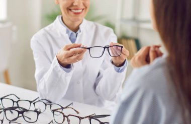 Göz doktorunun hastaya gözlük seçmesinde yardımcı olması için doktorun ellerini kapatın. Danışmanlık sırasında tıbbi reçete ve göz bakımı hizmetleri sunma, optalmolojiye odaklanma.