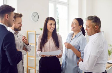Bir grup ofis çalışanı iş yerlerinde dikilip iletişim kuruyor, yakın çekimde. Takımda bölünme kavramı. Bir tartışmadaki bir adam çoğunluğun görüşüne katılmaz, tuhaflık...