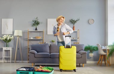 Neşeli kadın gezgin sonunda yaz tatili başladığında neşeli bir ruh hali içindeydi. Tatilini planlıyordu. Oturma odasında bavulunun yanında tasasız bir şekilde dans ediyordu. Turizm ve seyahat kavramı