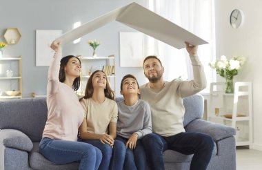 İki çocuklu genç bir aile derme çatma çatının altında oturup hayallerindeki evi hayal ediyorlar. Aile kanepeye oturmuş kafalarının üstünde büyük bir karton parçası tutuyorlar. Aile için konut kavramı.