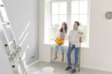 Genç çift mutlu ressamlar yeni bir daire inşa etme fikri, boya fırçasıyla duvar boyama, odanın taşınmasını tamamlama, bina onarımı, yenileme, yenileme, birlikte yeni bir hayata başlama