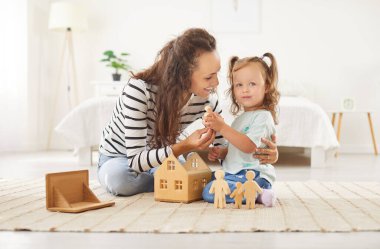 Genç mutlu anne evdeki oturma odasında küçük tatlı bir kızla eğitici tahta oyuncaklarla oynuyor. Kadın ebeveyn kızıyla vakit geçiriyor. Aile eğlencesi ve insan konsepti.