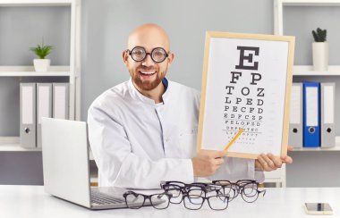 Komik ve gülümseyen adam göz doktoru ya da optometrist gözlüklerle çevrili alfabe tablosu kullanarak görüş kontrolü yapıyor. Oftalmoloji, sağlık hizmetinin bir tarafını gösteriyor.