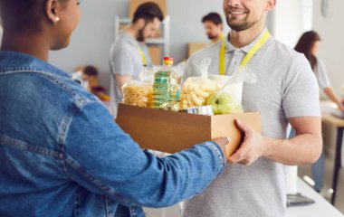 Kafkasyalı mutlu bir adamın Afrika kökenli Amerikalı bir mülteci kadına yardım merkezinde yemek verirken yakın plan çekimleri. Yardımseverlik, yardım, bağış ve yardım.