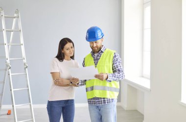 Mimar ve müşteri ya da müşteri, yaklaşan ev inşaatı veya yenileme projesinin planını gözden geçiriyorlar. Taslak üzerinde işbirliği yapıyorlar, yeni ev için önemli ayrıntıları planlıyorlar ve tartışıyorlar..