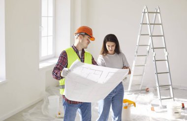 Müteahhit, tadilat sırasında bir müşterinin planını gösteriyor. Birlikte proje taslağını tartışıyor, inşaat detaylarını planlıyor ve başarılı bir sonuç için maliyetleri hesaplıyorlar..